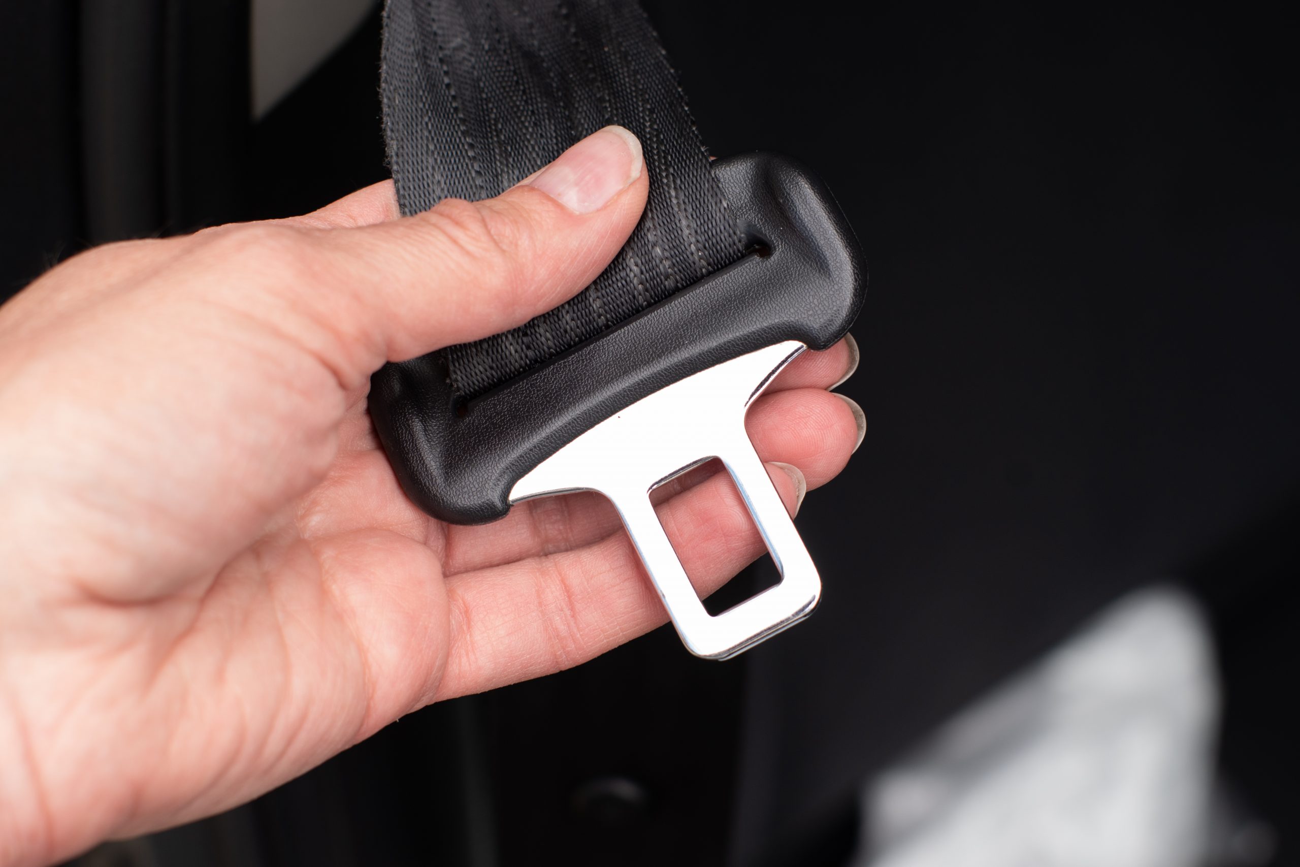 Close up of a woman's hand fastening seat belt while sitting inside a car for safety before riding on the road.